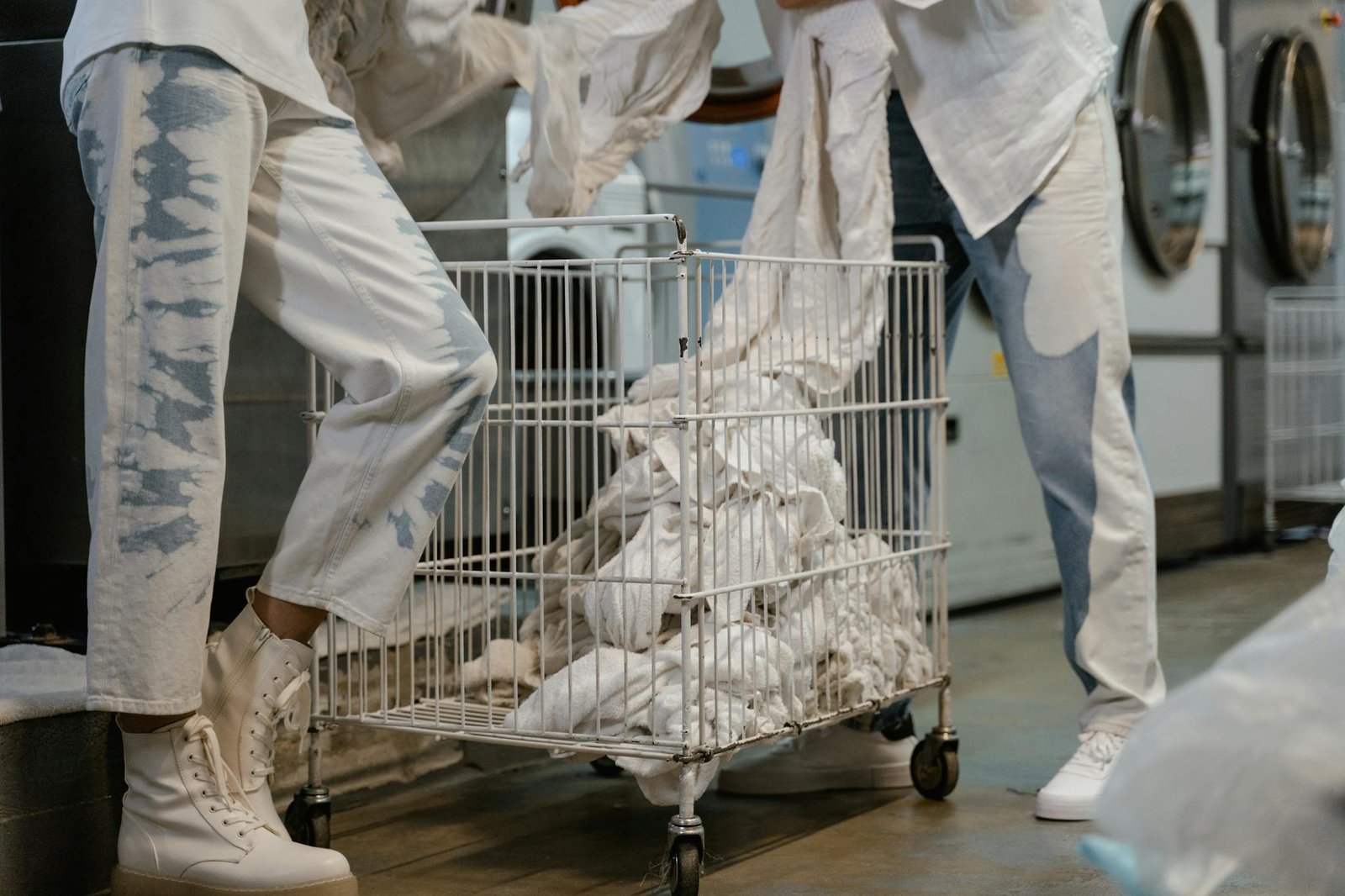 two individuals loading laundry into washers at